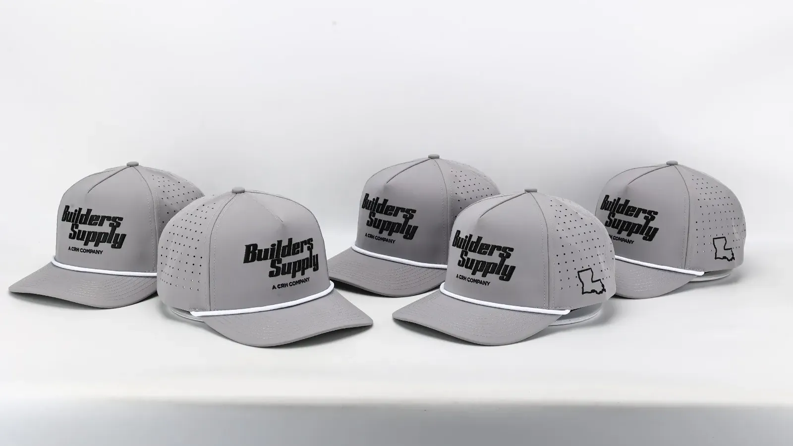 Five grey Builders Supply rope hats with embroidered logos, lined up on a table